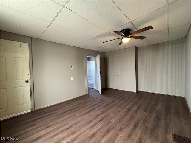 empty room featuring a paneled ceiling, visible vents, a ceiling fan, wood finished floors, and baseboards