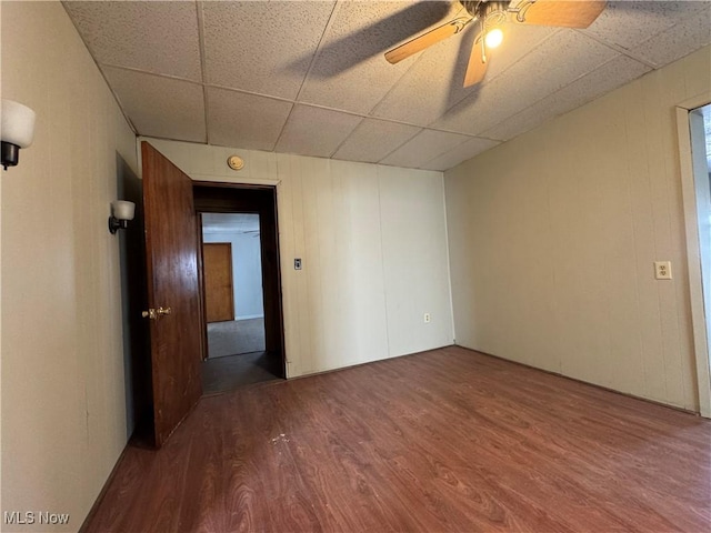 unfurnished room featuring a ceiling fan, a drop ceiling, and wood finished floors