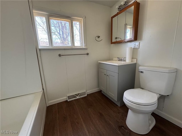 full bath featuring toilet, wood finished floors, vanity, visible vents, and baseboards