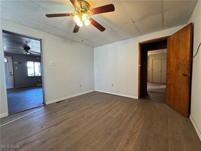 empty room with a ceiling fan, wood finished floors, visible vents, and baseboards