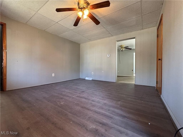 empty room featuring a ceiling fan, a paneled ceiling, and wood finished floors