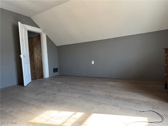 bonus room with visible vents, vaulted ceiling, and wood finished floors