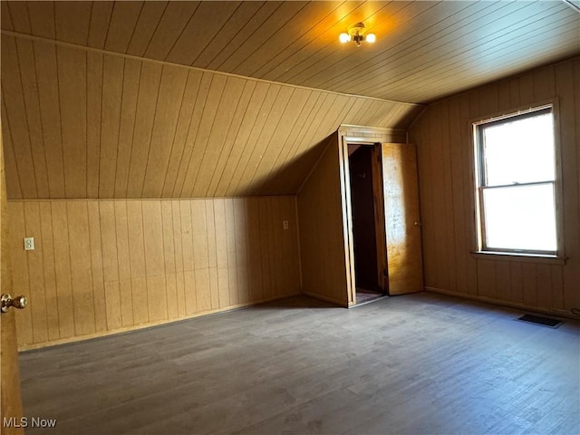 additional living space with lofted ceiling, wood walls, visible vents, and wood finished floors