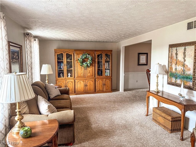 living room with carpet floors, visible vents, and a textured ceiling