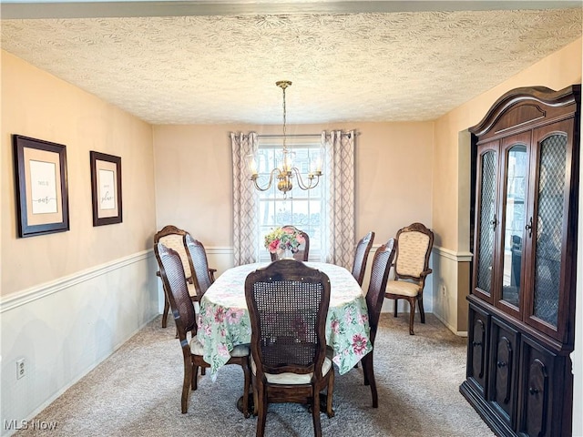 carpeted dining space featuring baseboards, a chandelier, and a textured ceiling