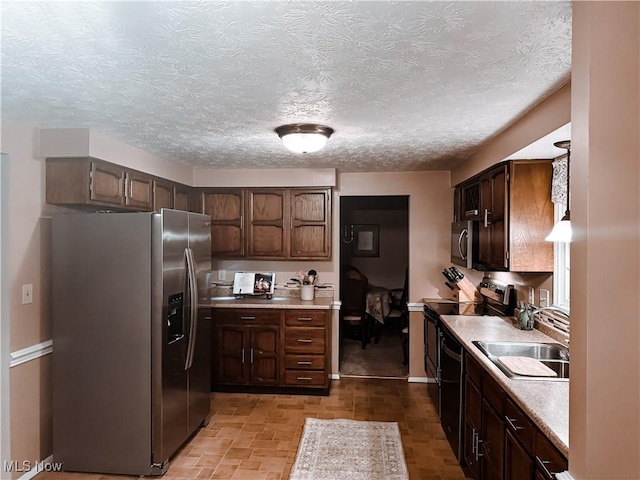 kitchen with stainless steel appliances, light countertops, a sink, and dark brown cabinets