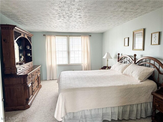 bedroom featuring a textured ceiling and light colored carpet