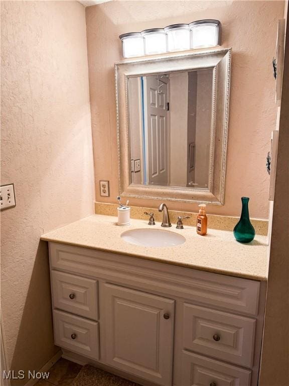 bathroom featuring a textured wall and vanity