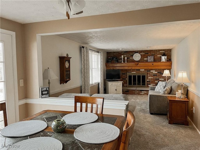 dining space featuring carpet floors, a fireplace, and a textured ceiling