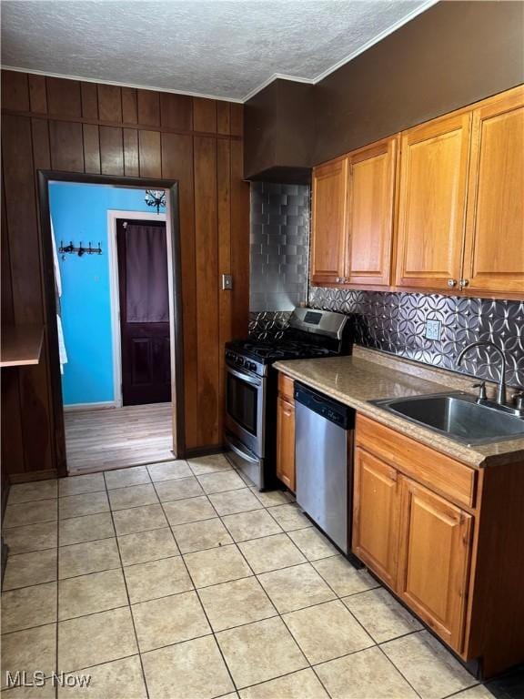 kitchen with stainless steel appliances, light tile patterned floors, a sink, and tasteful backsplash