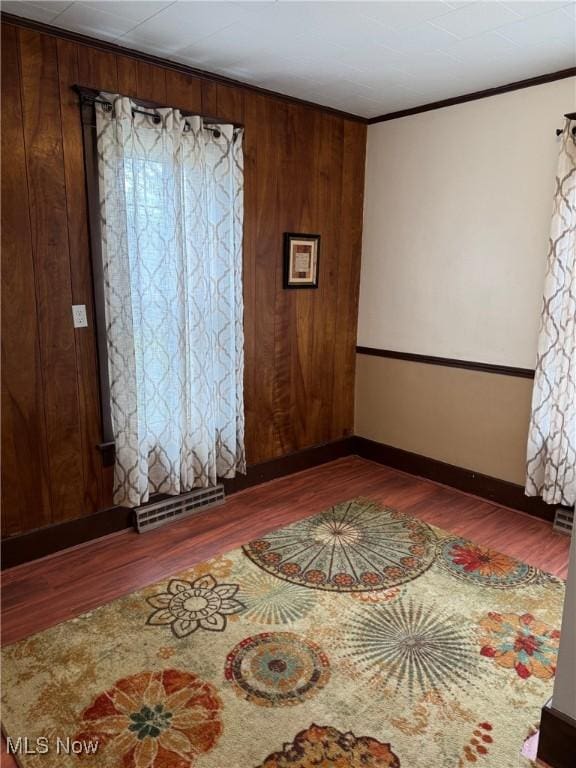 spare room with ornamental molding, visible vents, baseboards, and wood finished floors