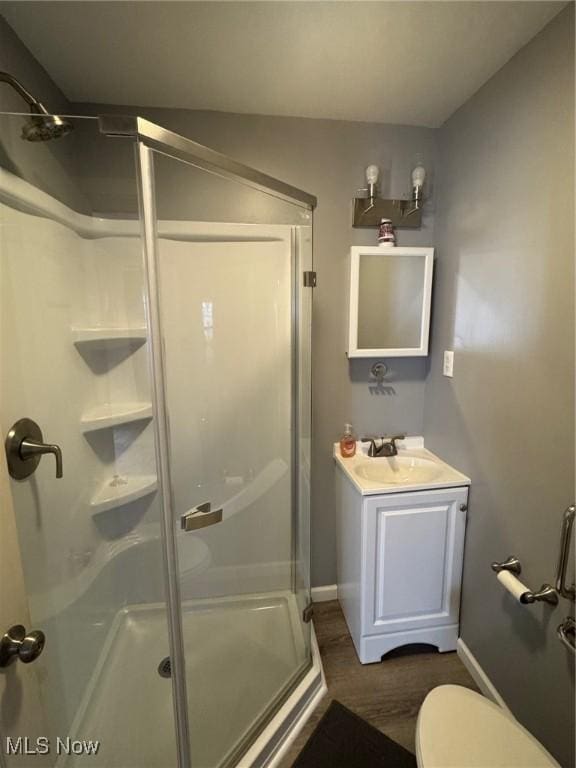 full bathroom featuring toilet, a stall shower, baseboards, and vanity