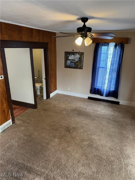 carpeted empty room featuring baseboards, a ceiling fan, and crown molding