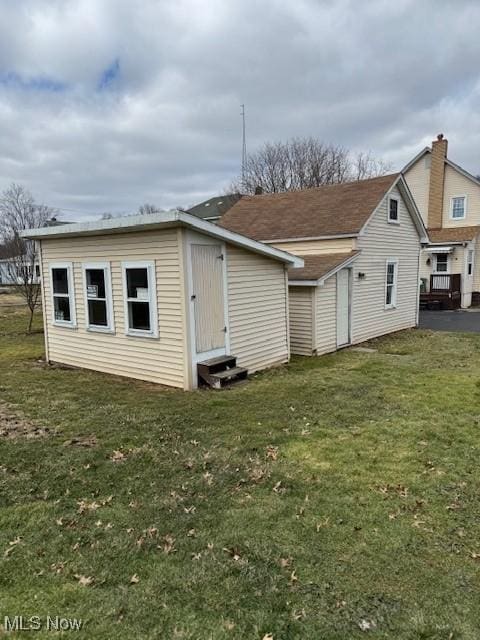 back of house featuring entry steps and a yard