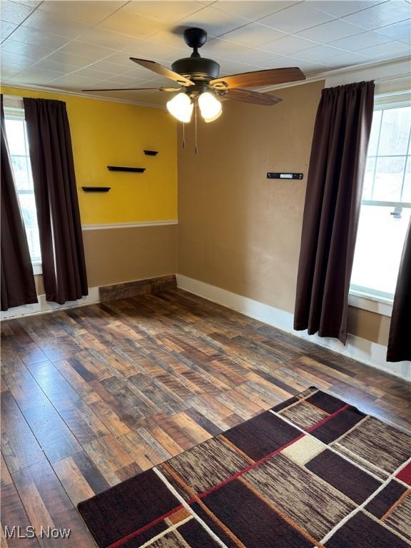 unfurnished room featuring ornamental molding, wood finished floors, a ceiling fan, and baseboards