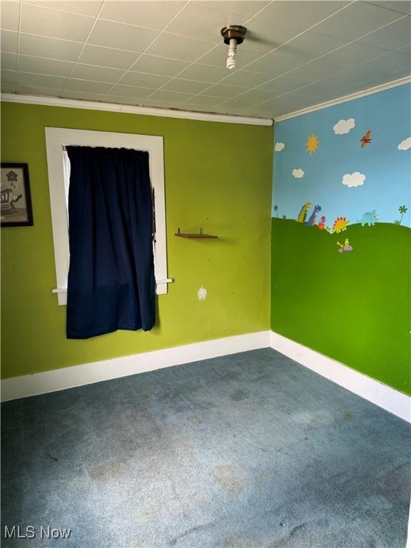 carpeted spare room with baseboards and crown molding