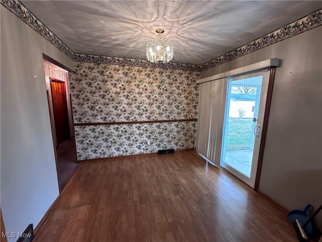 unfurnished dining area with a chandelier, visible vents, baseboards, and wood finished floors