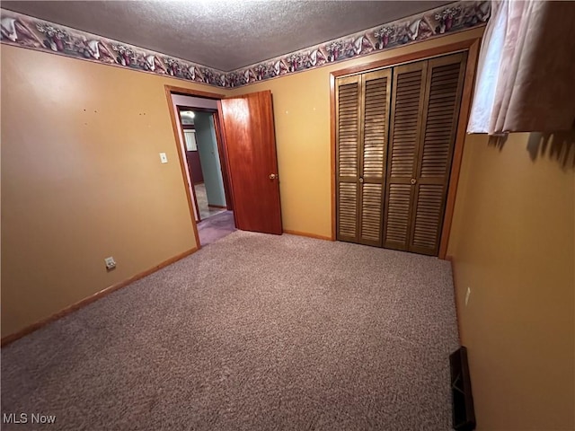 unfurnished bedroom with a closet, a textured ceiling, baseboards, and carpet flooring