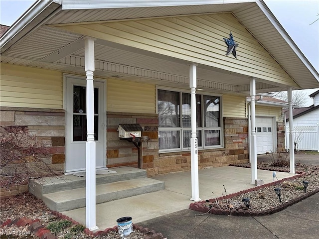 view of exterior entry with stone siding, a porch, and fence