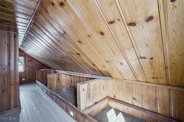 additional living space with wooden walls, wooden ceiling, hardwood / wood-style flooring, and vaulted ceiling