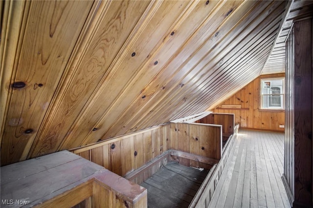 additional living space with vaulted ceiling, wood walls, and hardwood / wood-style floors