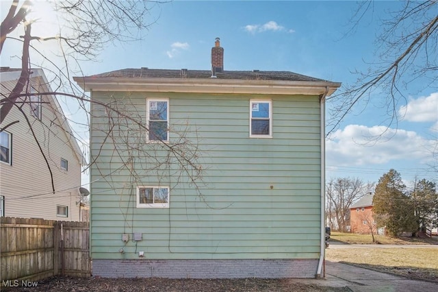 view of home's exterior featuring fence and a chimney