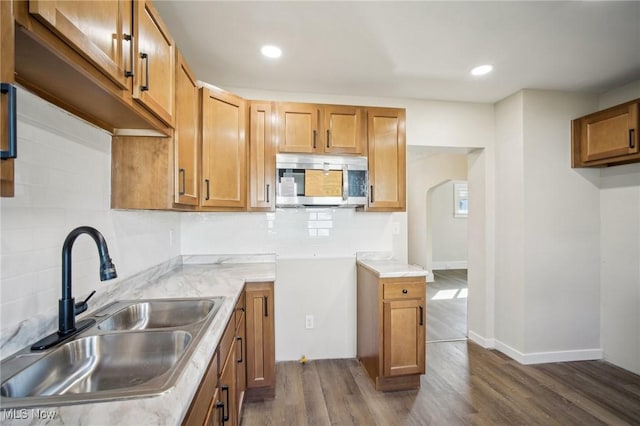 kitchen featuring dark wood finished floors, stainless steel microwave, tasteful backsplash, and a sink