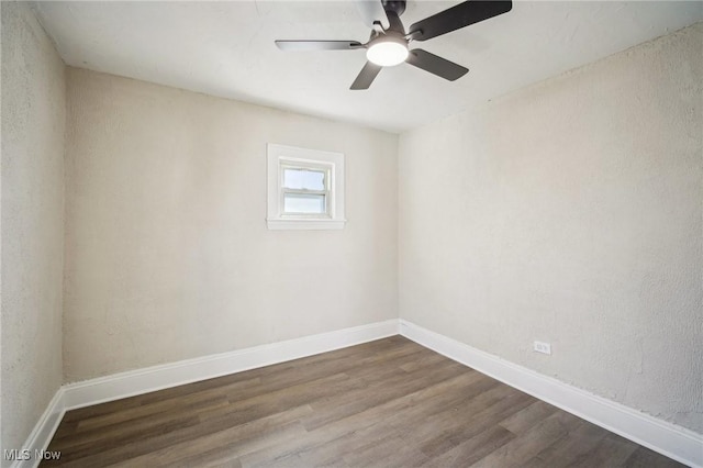 unfurnished room featuring baseboards, dark wood-style floors, and a ceiling fan