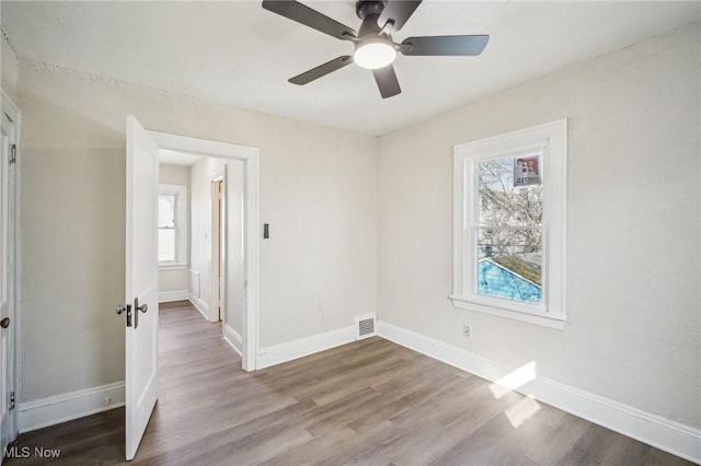 unfurnished bedroom with ceiling fan, visible vents, baseboards, and wood finished floors