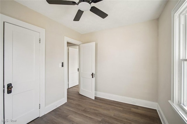 unfurnished bedroom featuring ceiling fan, dark wood-type flooring, and baseboards