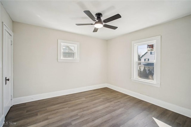 spare room with plenty of natural light, wood finished floors, and baseboards