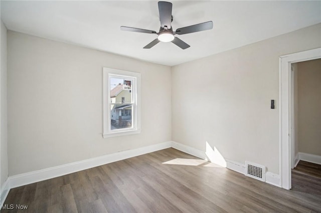 empty room with wood finished floors, baseboards, visible vents, and ceiling fan