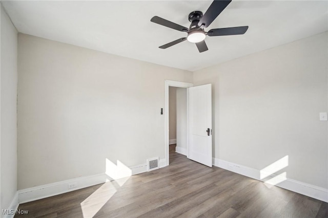 spare room with a ceiling fan, wood finished floors, visible vents, and baseboards