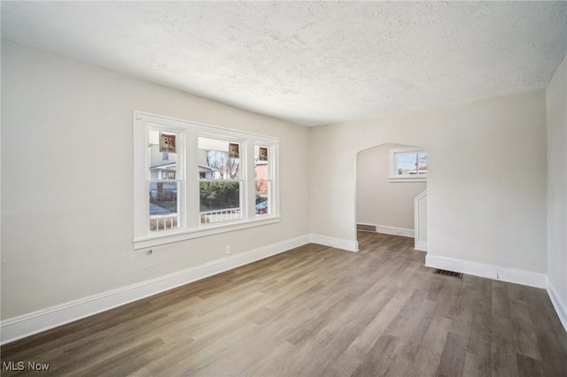 unfurnished room featuring wood finished floors, baseboards, and a textured ceiling