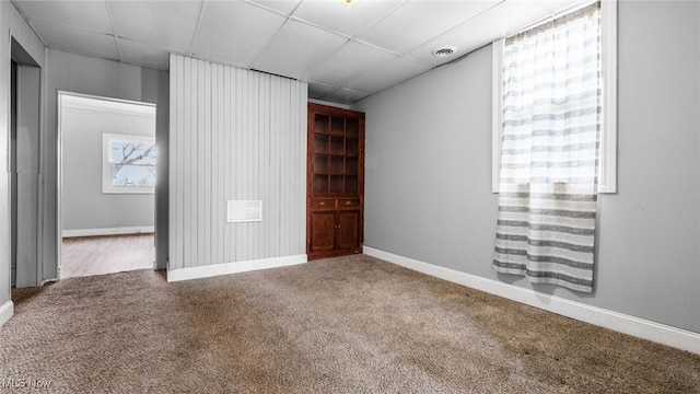 unfurnished bedroom featuring carpet floors, baseboards, and a drop ceiling