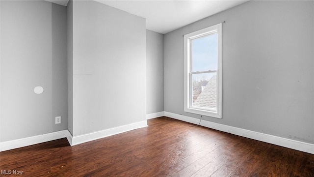 unfurnished room with dark wood-type flooring and baseboards