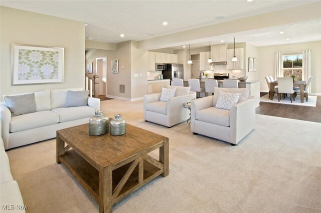 living room with light carpet, visible vents, baseboards, and recessed lighting