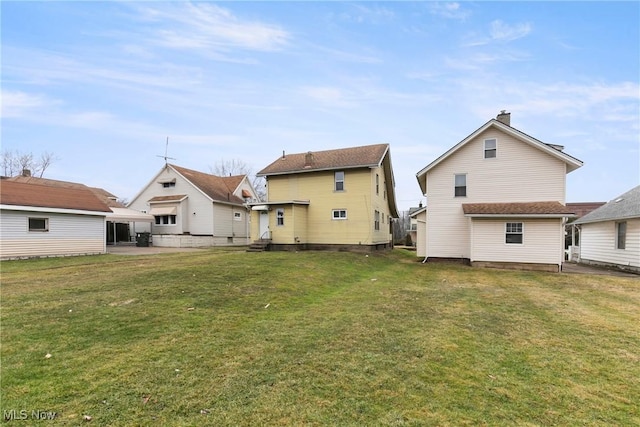 rear view of house featuring entry steps, a patio area, a lawn, and a chimney