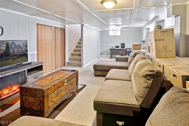 carpeted living area with stairs and a glass covered fireplace