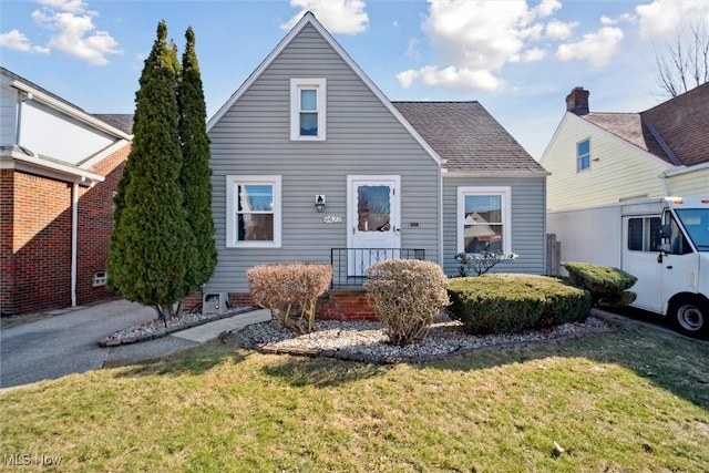 view of front of property with a shingled roof and a front yard