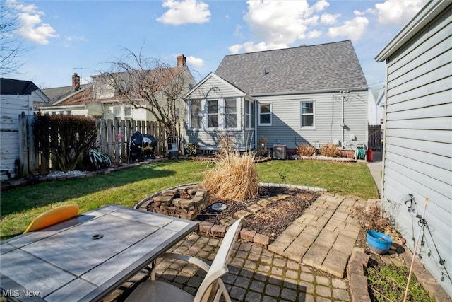 back of house featuring roof with shingles, a yard, a patio area, fence, and a fire pit