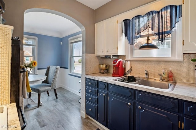 kitchen with arched walkways, light countertops, a sink, and blue cabinetry