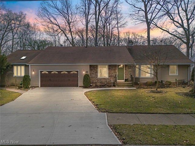 single story home with an attached garage, a front lawn, and concrete driveway