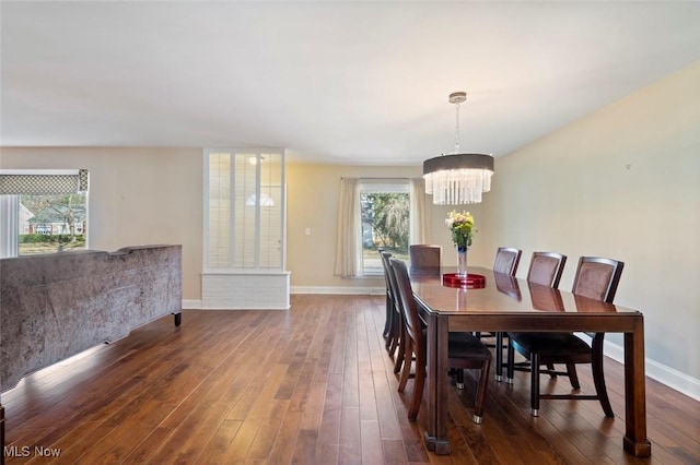 dining space featuring dark wood-style floors, baseboards, and an inviting chandelier