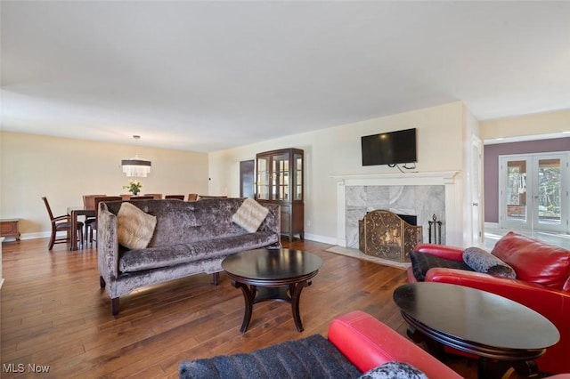 living room with baseboards, a high end fireplace, hardwood / wood-style floors, and french doors