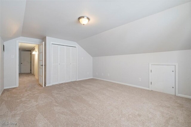 bonus room with lofted ceiling, light colored carpet, and baseboards