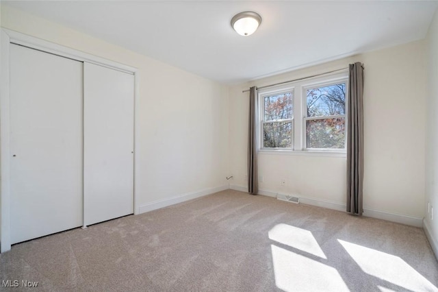 unfurnished bedroom with carpet, a closet, visible vents, and baseboards