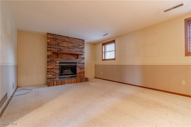 unfurnished living room featuring carpet, visible vents, a fireplace, and baseboards