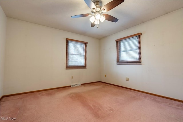 spare room with light colored carpet, a healthy amount of sunlight, visible vents, and baseboards