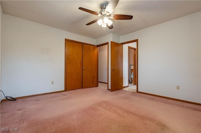 unfurnished bedroom featuring light carpet, ceiling fan, a closet, and baseboards